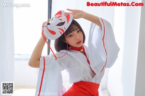 A woman in a red and white dress posing on a bed.