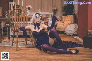 A woman in a purple outfit is sitting on a bed.