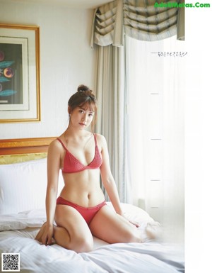 A woman in a black bikini sitting on a counter.