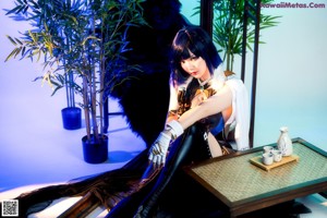 A woman laying on top of a table next to a plant.
