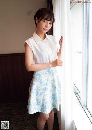 A woman in a striped shirt and white shorts posing for a picture.