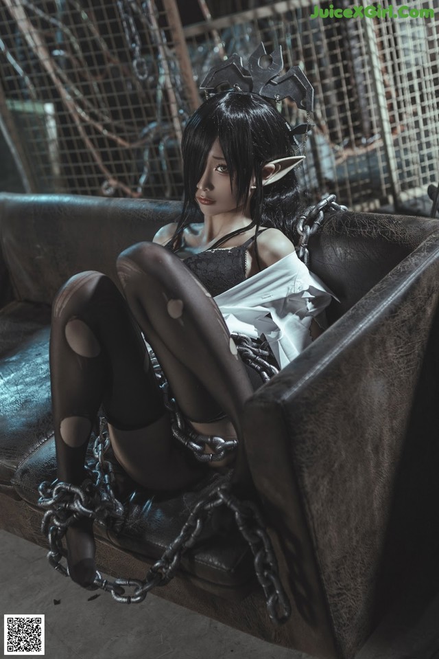 A woman sitting on a couch with chains around her legs.