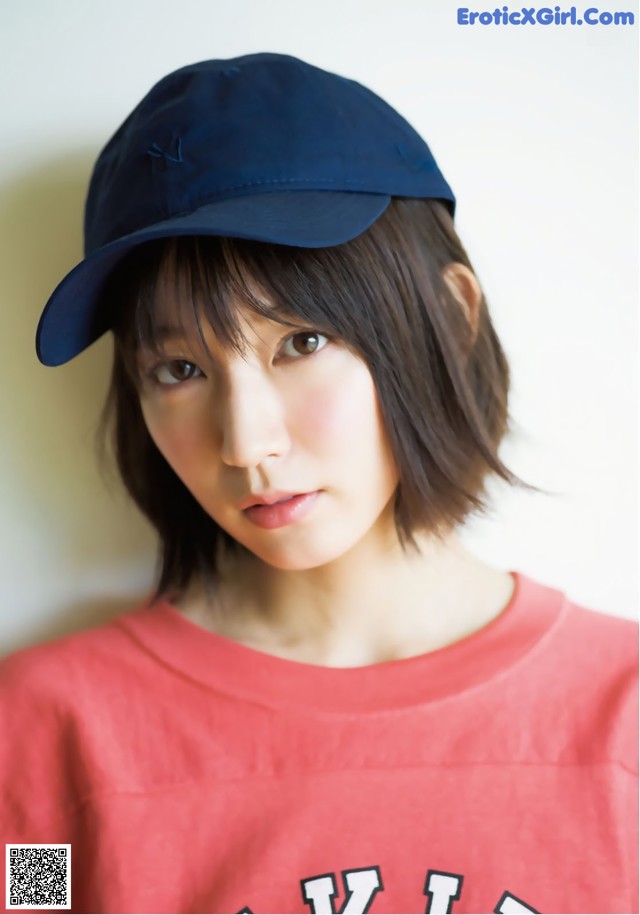 A woman wearing a red shirt and a blue baseball cap.