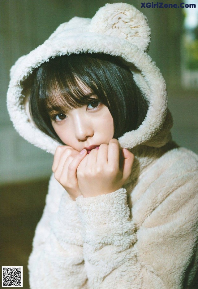 A woman in a teddy bear hoodie is posing for a picture.