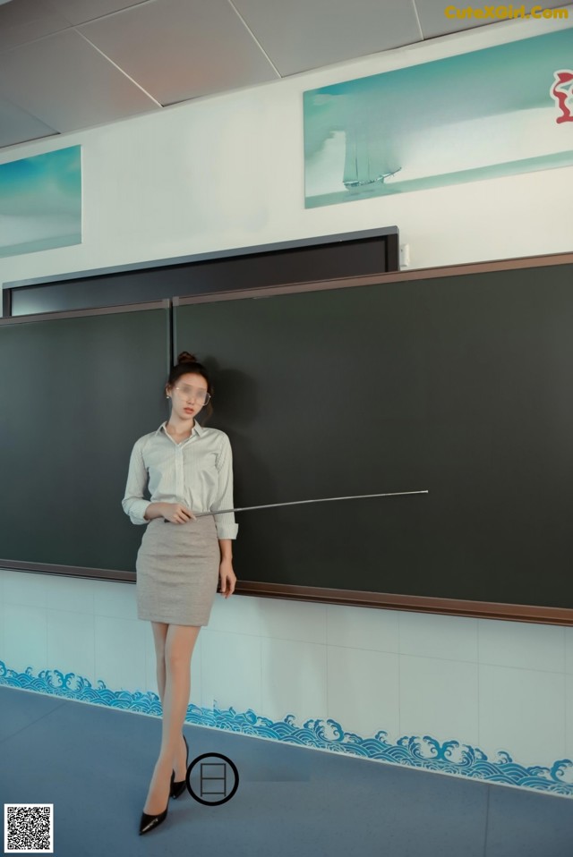 A woman standing in front of a blackboard in a classroom.