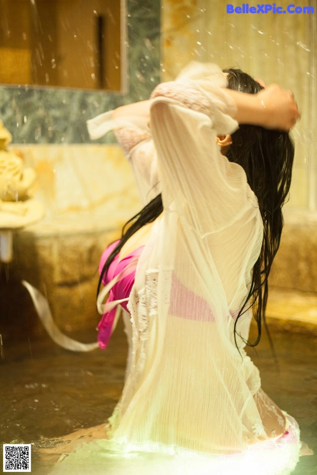 A woman in a bathtub with a veil over her head.