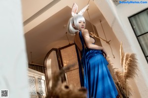 A woman in a blue dress and bunny ears posing for a picture.