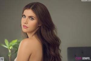 A woman with long brown hair is posing naked on a bed.