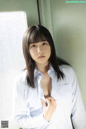 A woman in a school uniform standing in front of a window.