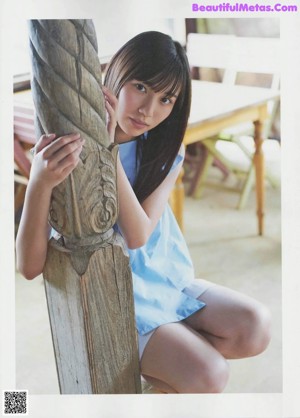 A woman sitting on top of a wooden bench.