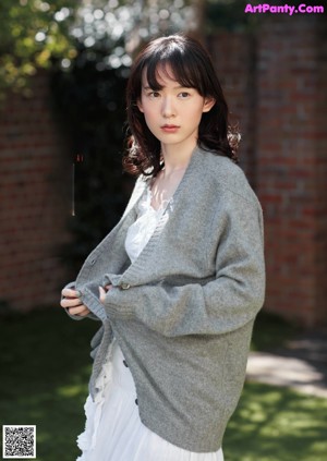 A woman in a red and white dress standing in a park.