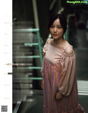 A woman in a pink dress standing in front of a window.