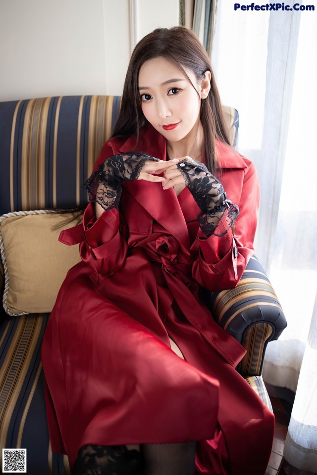 A woman in a red robe sitting on a couch.