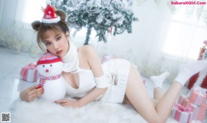 A woman in lingerie sitting next to a christmas tree.