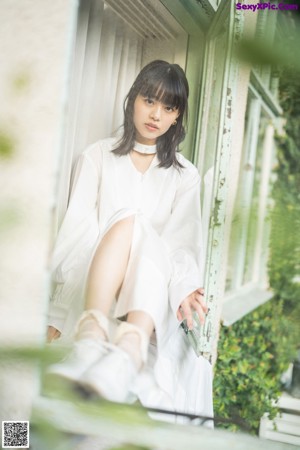 A woman in a white dress sitting on a bench.