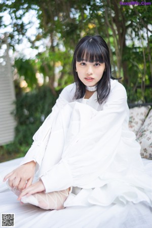 A woman with long black hair wearing a white coat.