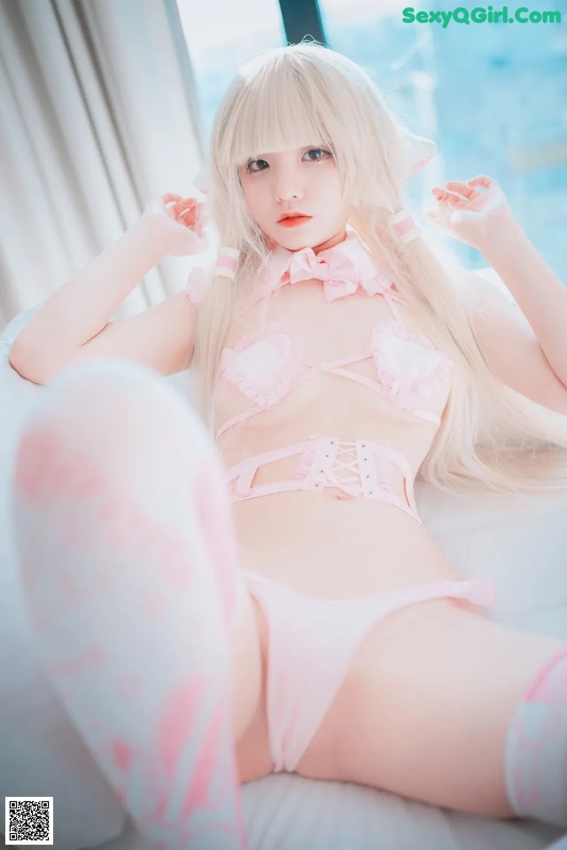 A woman in a pink lingerie sitting on a white couch.