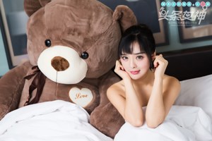 A woman sitting on a bed holding a teddy bear.