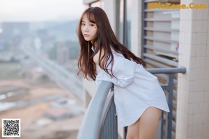 A woman in a white sweater and blue shorts posing for a picture.