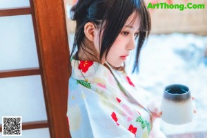 A woman in a kimono sitting on a wooden bench.