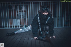 A woman in a black outfit is standing on a metal railing.