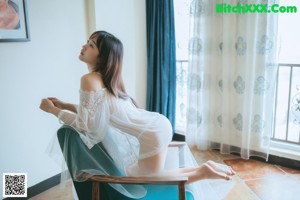 A woman laying on top of a bed in a white shirt.