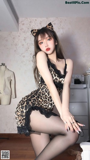 a woman in a leopard print dress and black stockings posing for the camera