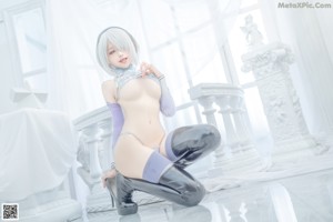 A woman in a blue and white outfit sitting on the floor.
