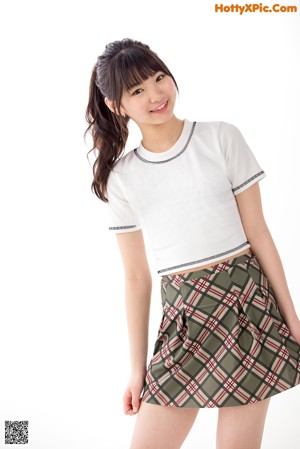 A young woman wearing a white shirt and plaid skirt.