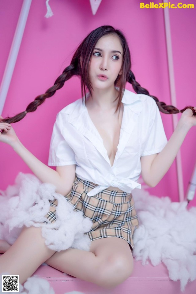 A woman sitting on top of a pink chair with long hair.