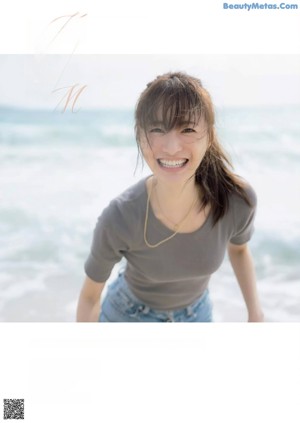 A woman wearing a white tank top and a silver necklace.