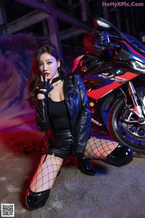 A woman sitting on top of a motorcycle in a garage.