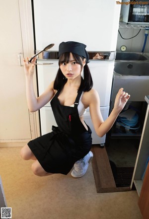 A woman in a white shirt and black skirt in a kitchen.