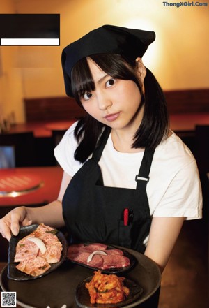 A woman in a white shirt and black skirt in a kitchen.