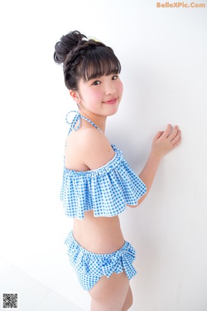 A woman in a blue and white gingham bikini standing on a scale.
