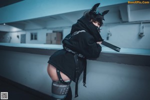 A woman in a black lingerie sitting on the ground.