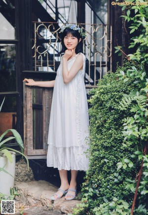 A woman in a white dress sitting on a chair.