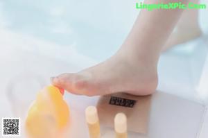 A woman sitting in a bathtub with her feet on the edge of the water.