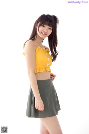 A woman in a yellow top and green skirt posing for a picture.